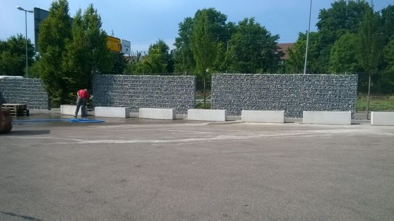 Gabionenwand als Abgrenzung einer großen befestigten Außenfläche.
