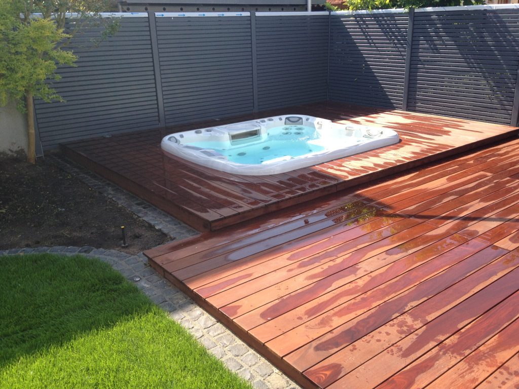 Whirlpool auf einer Holzterrasse mit abgestuften Dielen und dunklem Sichtschutz.