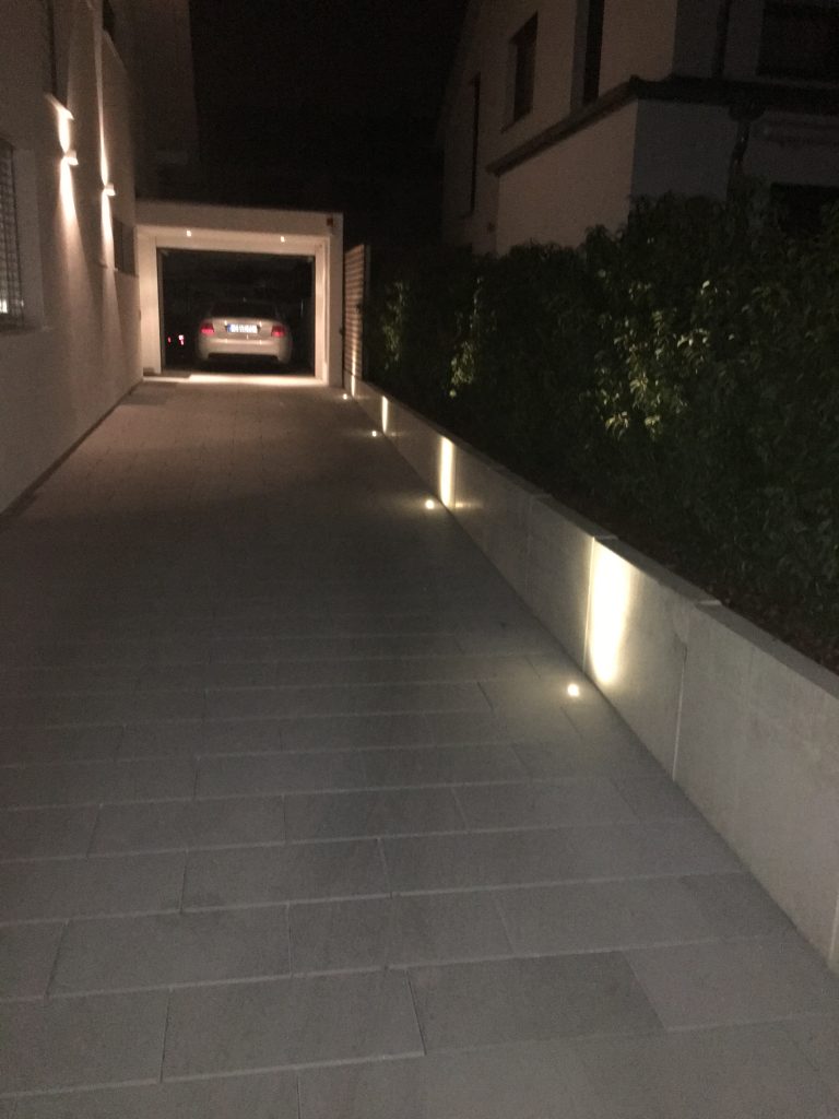 Gerader Hausweg mit in die seitliche Wand integrierten Leuchten.