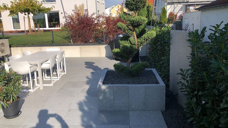 Terrassenbereich mit erhöhten Pflanzbeeten und geschwungenem Gartenweg.