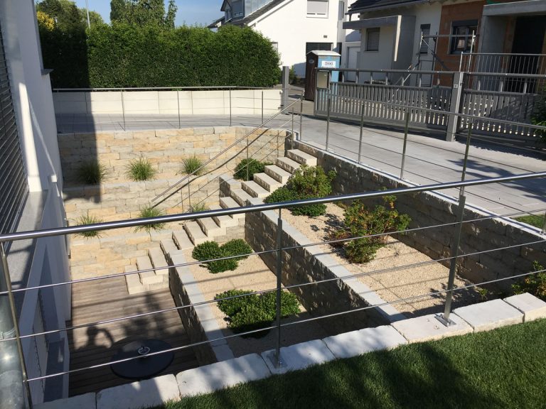 Terrassierter Lichthof mit Natursteinmauern und bepflanzten Ebenen.