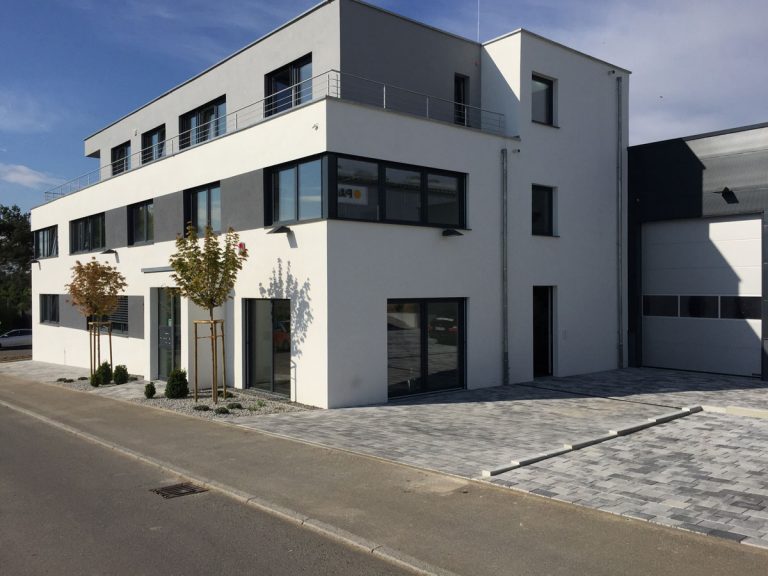 Gepflasterte Außenflächen rund um ein modernes Wohngebäude.