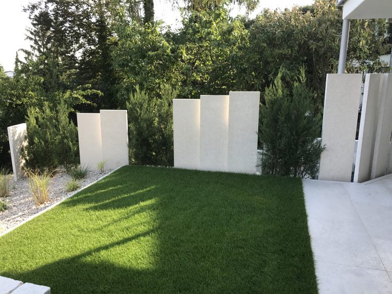 Gartenrasen mit hellem Sichtschutz und frisch angelegten Pflanzbereichen.