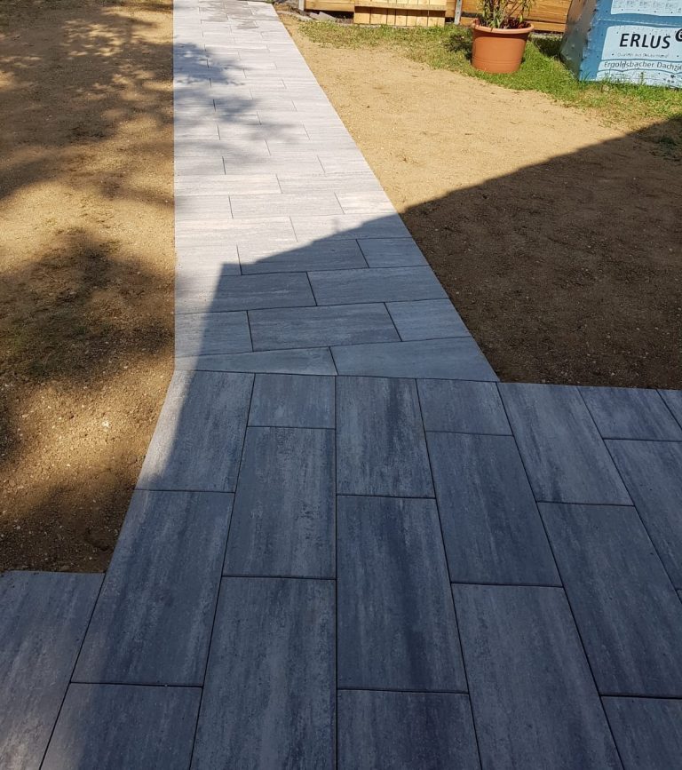 Neu verlegter Gartenweg aus länglichen grauen Platten.