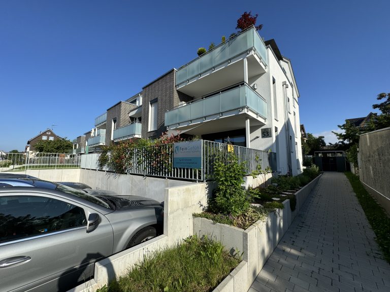 Seitlicher Zugang zu einem Wohnhaus mit begrünten Außenflächen.