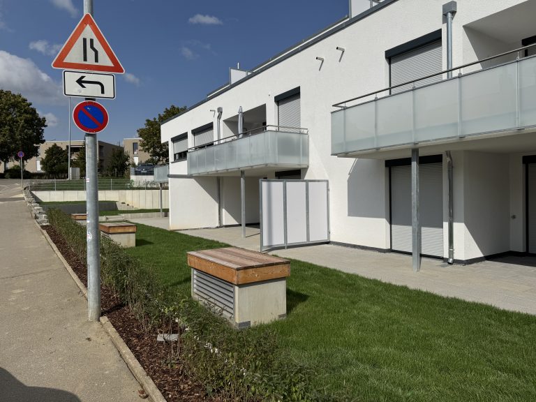 Moderne Wohnbebauung mit angelegten Rasenstreifen und niedrigen Einfassungen.