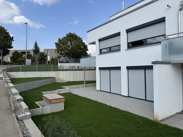 Gepflasterte Garagenzufahrt mit Rasenflächen und geraden Einfassungen.